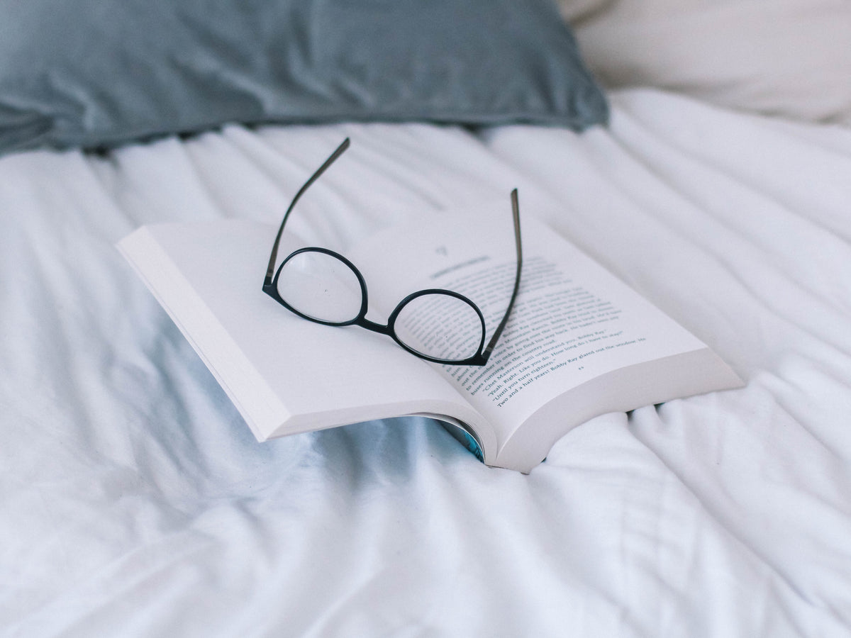 Boek en bril in bed 