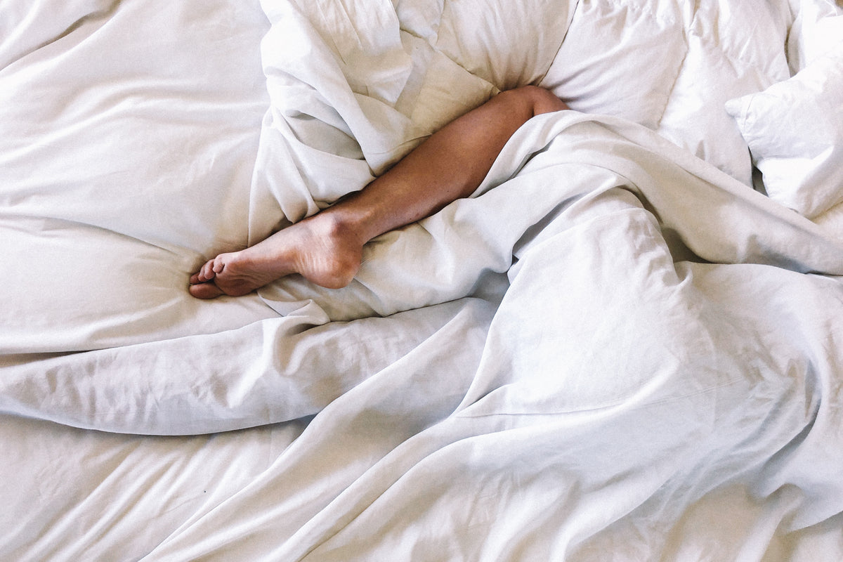 persoon in bed met witte lakens